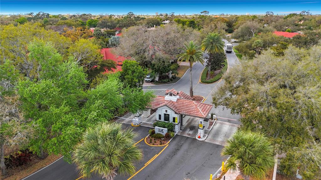 An aerial view shows the gated entrance to a residential community with a guardhouse — 1445 LANDINGS CIRCLE UNIT 69, SARASOTA, FL