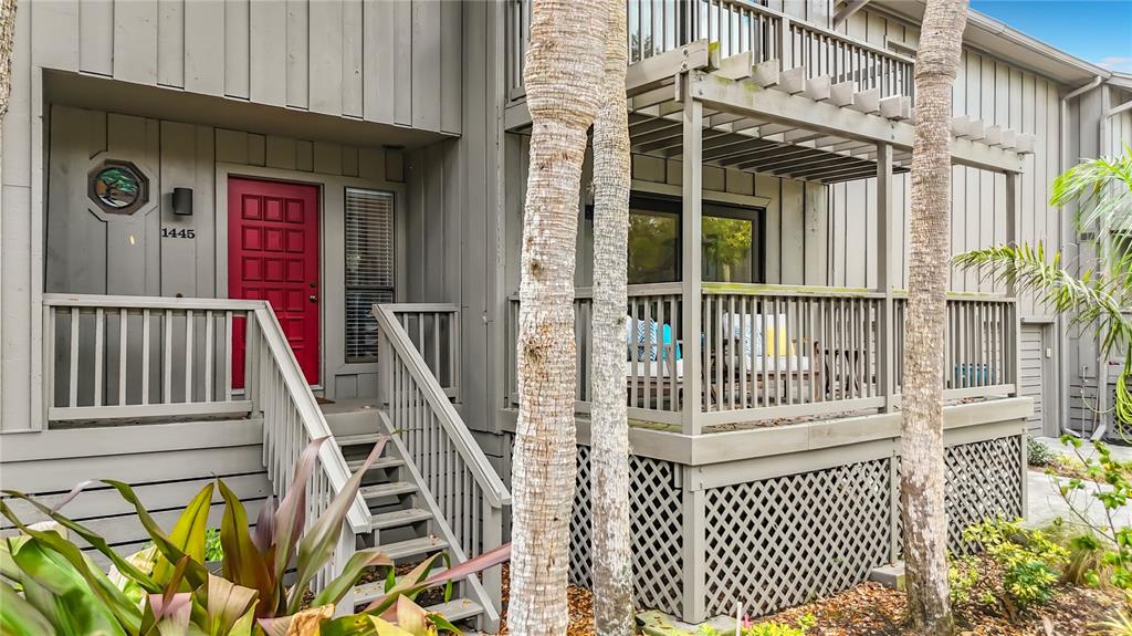 A gray two-story building features a red front door, a wooden staircase, and a deck — 1445 LANDINGS CIRCLE UNIT 69, SARASOTA, FL