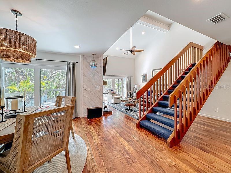 A dining area with a wooden staircase leads to a living room with vaulted ceilings — 1445 LANDINGS CIRCLE UNIT 69, SARASOTA, FL