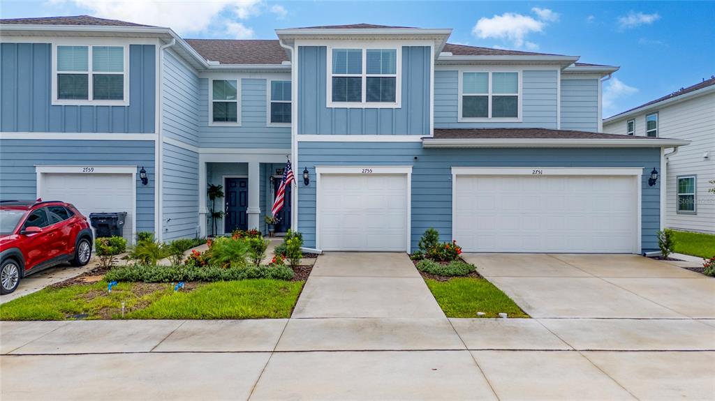 A multi-unit blue residential building features three garage doors, a front entrance, and a red car — 2755 FETCHING TRAIL, DAVENPORT, FL