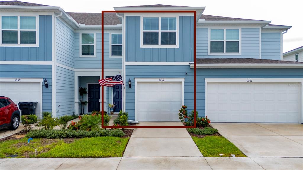 A blue two-story townhouse exterior features a white garage door and a front entrance — 2755 FETCHING TRAIL, DAVENPORT, FL