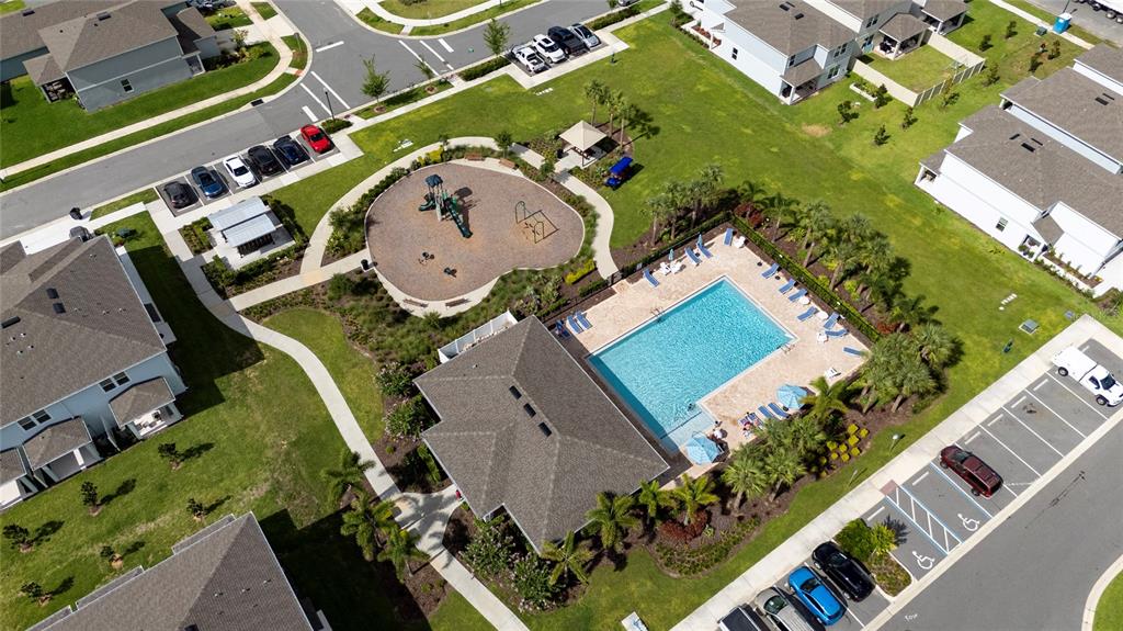 An aerial view shows a community pool, playground, and parking lot surrounded by residential homes — 2755 FETCHING TRAIL, DAVENPORT, FL