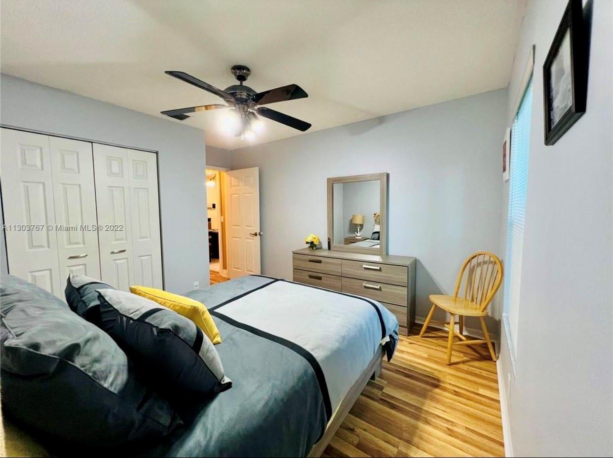 A bedroom features a bed, a dresser with a mirror, a wooden chair, and a ceiling fan — 6972 NW 19th Street, Margate FL 33063, MARGATE, FL