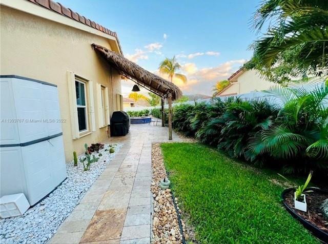 A backyard features a tiled patio, a thatched-roof pergola, and a white storage shed — 6972 NW 19th Street, Margate FL 33063, MARGATE, FL