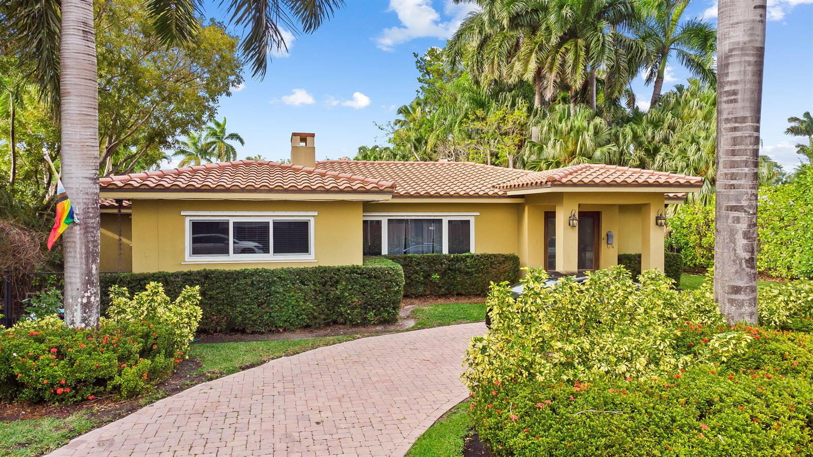 A single-story yellow house with a tile roof and a brick driveway surrounded by landscaping — 939 Buchanan Street, Hollywood FL 33019, HOLLYWOOD, FL