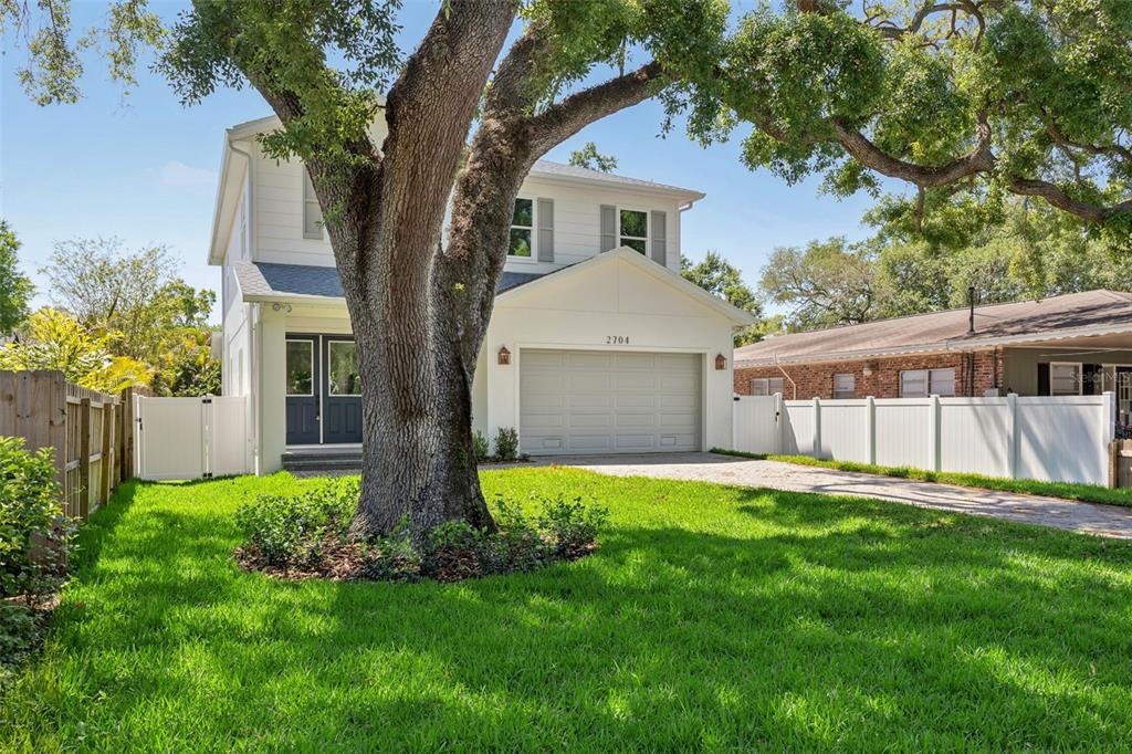 A two-story white house with a front-facing garage and a large tree in the yard — 2704 W TYSON AVENUE, TAMPA, FL