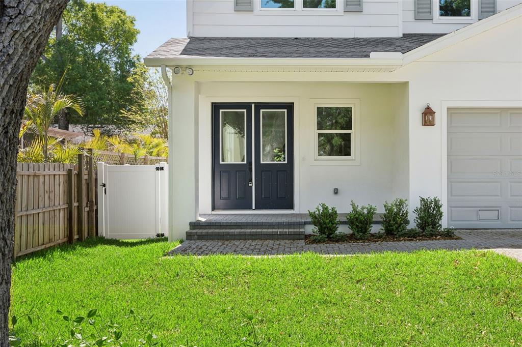 A white house exterior features a dark blue double front door and a paved walkway — 2704 W TYSON AVENUE, TAMPA, FL