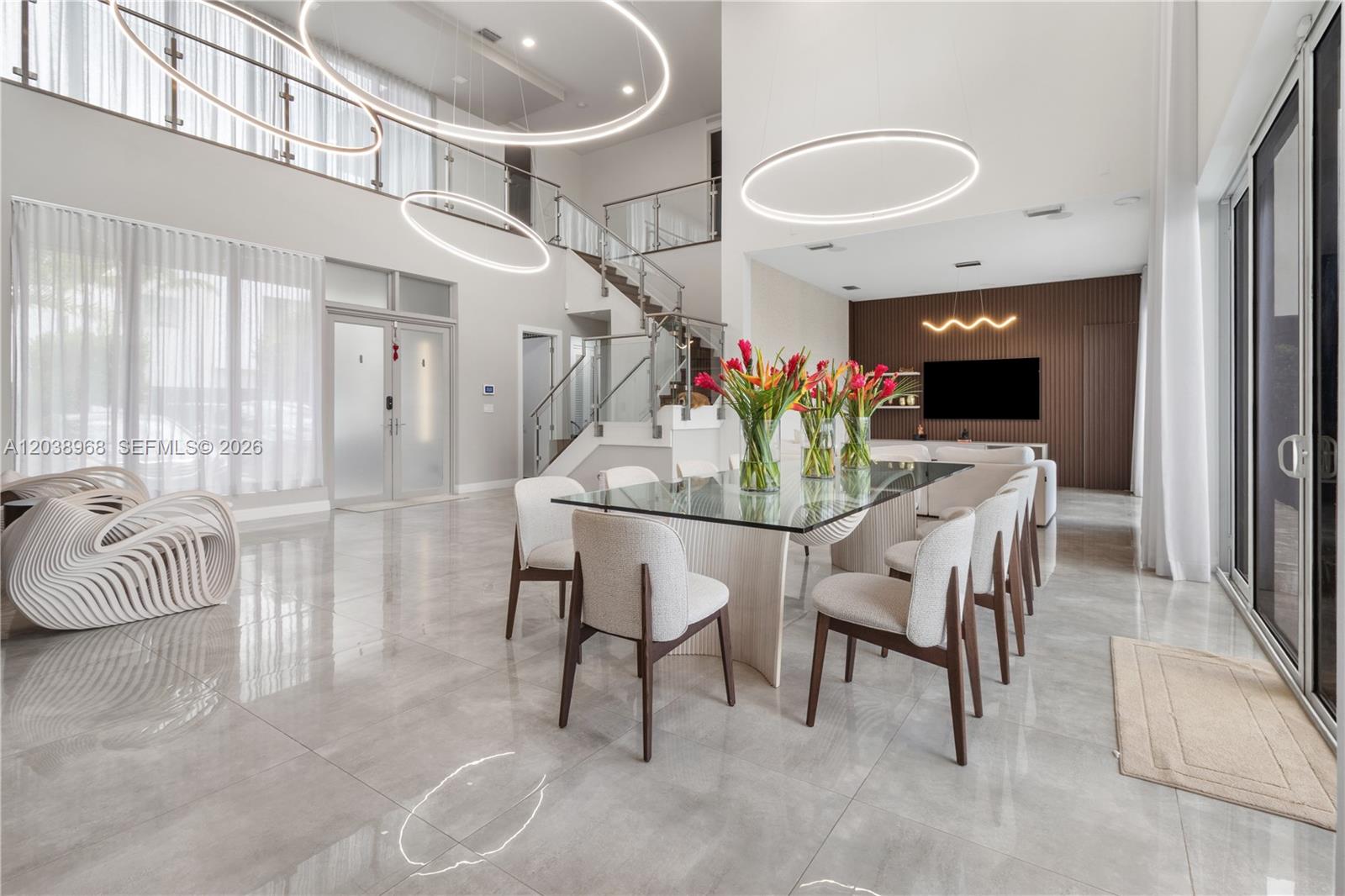 A modern dining room features a glass table, upholstered chairs, and large circular pendant lights — 10261 NW 74th Ter, Doral FL 33178, DORAL, FL