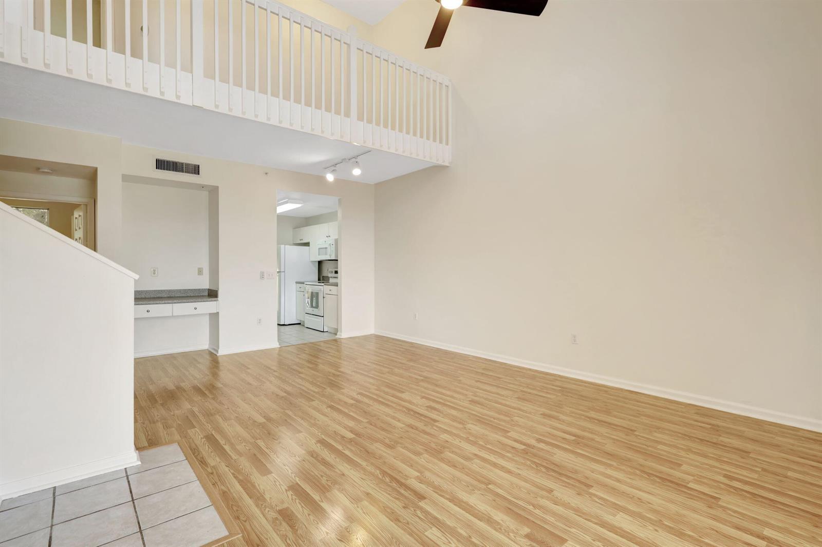 A living room with light wood flooring, a high ceiling, and a lofted balcony — 4812 S Central Boulevard # 24, Jupiter FL 33458, JUPITER, FL