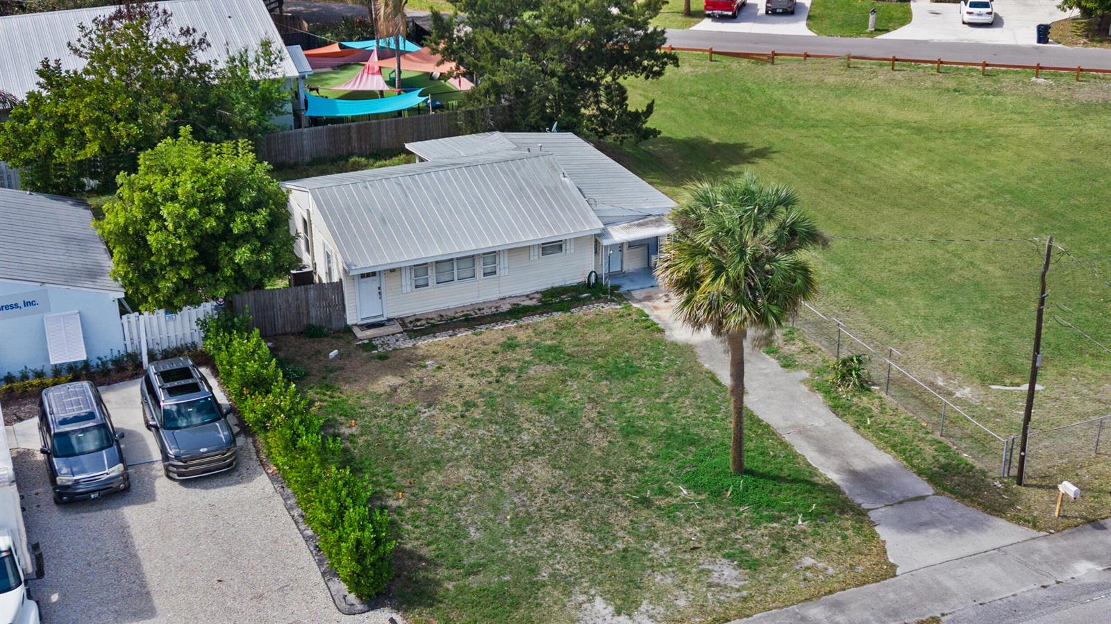 An aerial view shows a light-colored house with a metal roof and a palm tree — 820 SW Palm City Road, Stuart FL 34994, STUART, FL