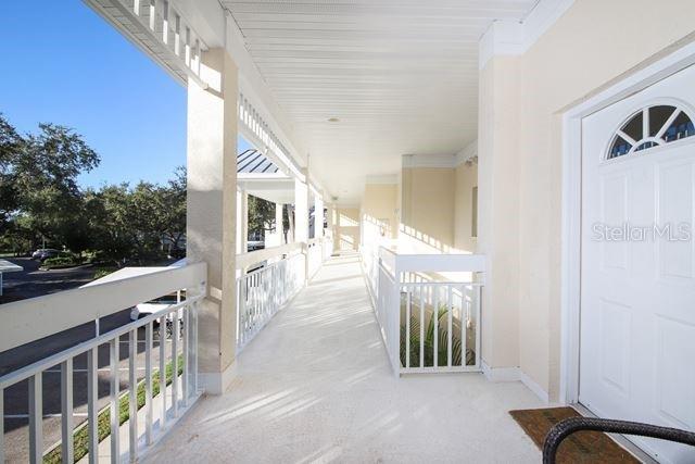 An outdoor covered walkway with white railings leads to a white front door — 3605 54TH DRIVE W UNIT 202, BRADENTON, FL