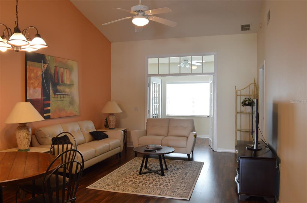 A living room features a vaulted ceiling, a beige sofa, and dark wood flooring — 3605 54TH DRIVE W UNIT 202, BRADENTON, FL