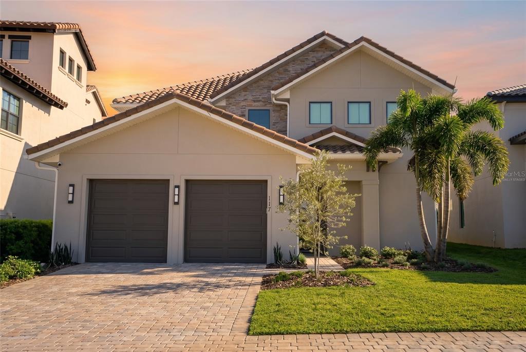 A two-story suburban house with a two-car garage, stone accents, and a paved driveway — 16046 VETTA DRIVE, BELLA COLLINA, FL