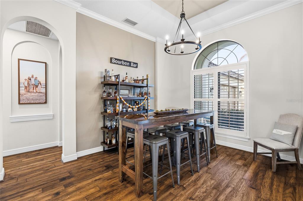 A dining room features a wooden bar table, metal stools, and a wall-mounted liquor shelf — 16406 CHAPMAN CROSSING DRIVE, LITHIA, FL