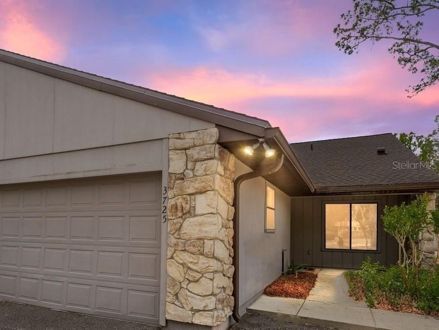 A house exterior features a garage, stone pillar, and a walkway leading to the entrance — 3725 NW 58TH PLACE, GAINESVILLE, FL