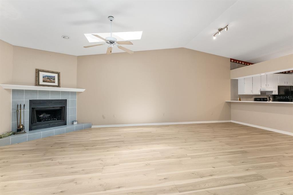 A living room features light wood-look flooring, a corner fireplace, and a vaulted ceiling — 3725 NW 58TH PLACE, GAINESVILLE, FL