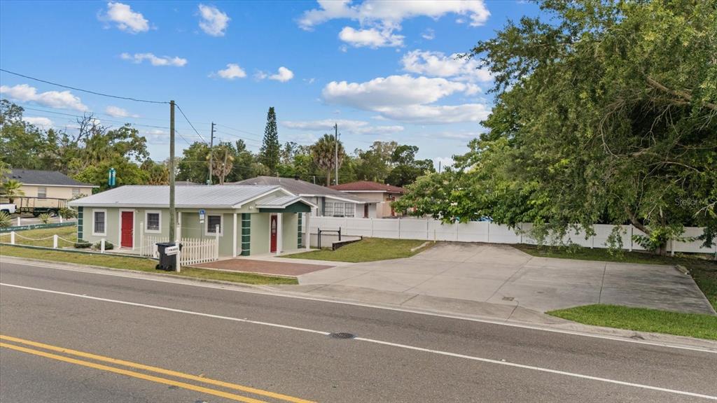 A light green single-story building with a large concrete parking area sits beside a road — 6511 MAIN STREET, NEW PORT RICHEY, FL