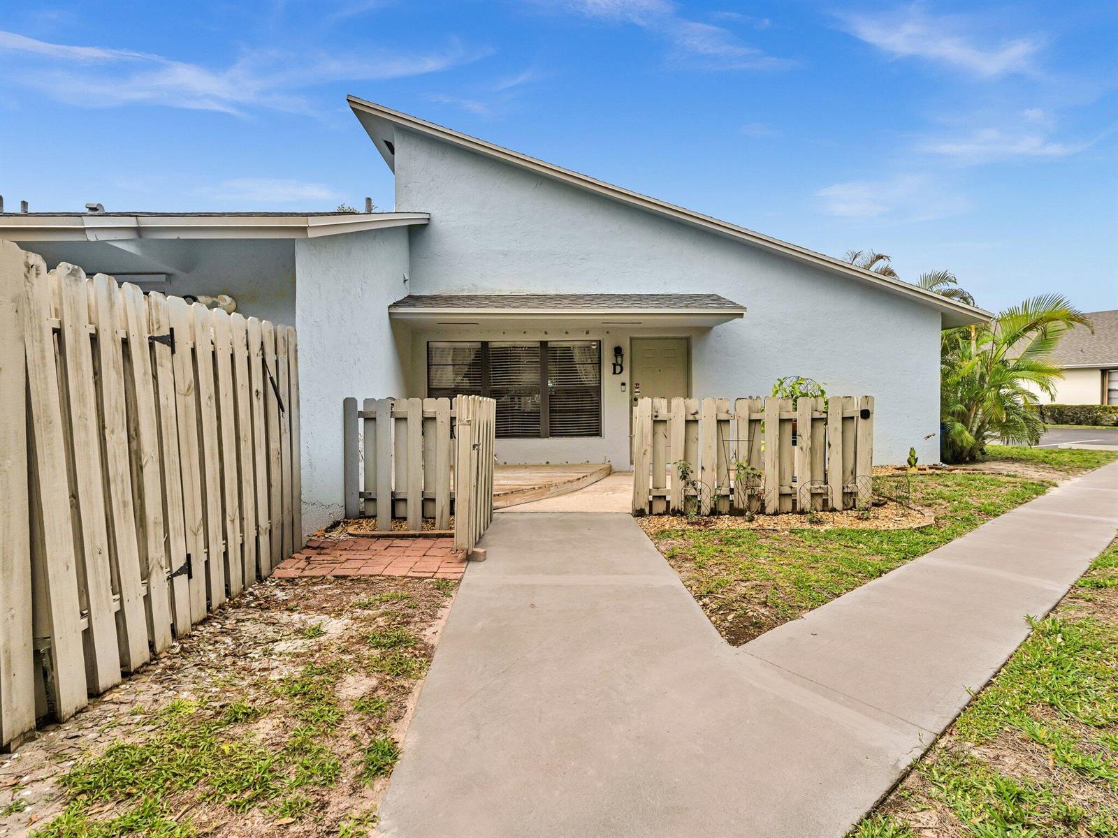 A light blue single-story home features a concrete walkway leading to a small fenced patio — 431 Jupiter Lakes Boulevard # 2124d, Jupiter FL 33458, JUPITER, FL