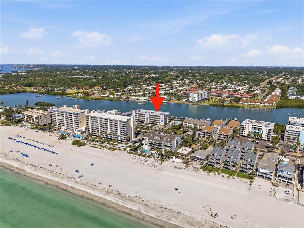 An aerial view shows a multi-story beachfront condominium complex with a red arrow pointing down — 20001 GULF BOULEVARD UNIT 405, INDIAN SHORES, FL