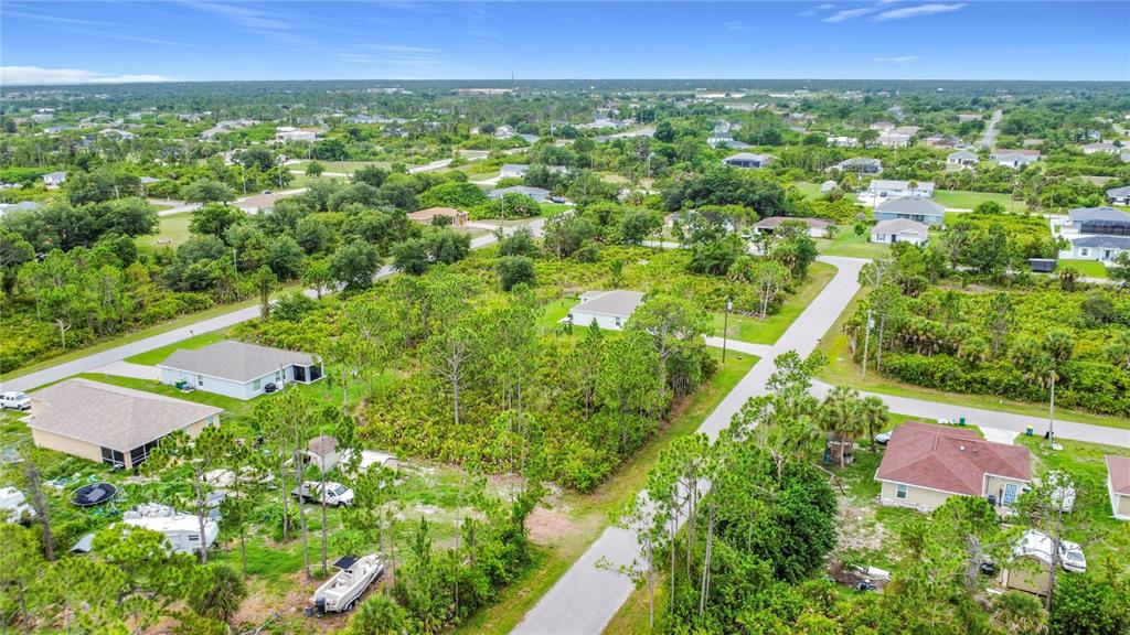 An aerial view shows a vacant, wooded residential lot situated between several suburban houses — 5464 MURPHY STREET, PORT CHARLOTTE, FL