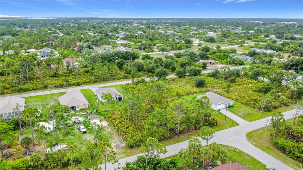 An aerial view shows several single-family homes surrounded by wooded lots and paved roads — 5464 MURPHY STREET, PORT CHARLOTTE, FL