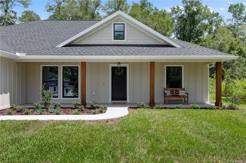 A single-story house with board-and-batten siding, a covered porch, and a dark front door — 3053 E ANGELINA STREET, INVERNESS, FL
