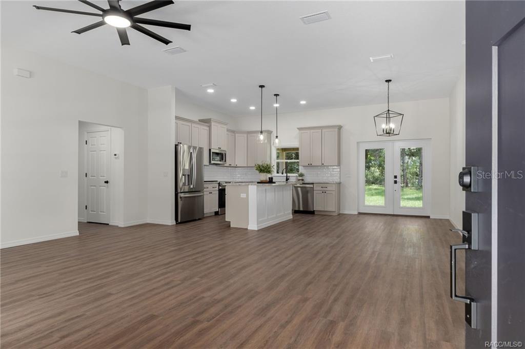 An open-concept kitchen and living area features light-colored cabinetry, a center island, and wood-look flooring — 3053 E ANGELINA STREET, INVERNESS, FL