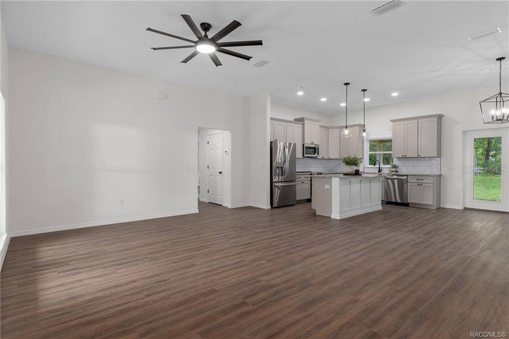 An open-concept living room and kitchen with wood-look flooring, gray cabinetry, and a ceiling fan — 3053 E ANGELINA STREET, INVERNESS, FL