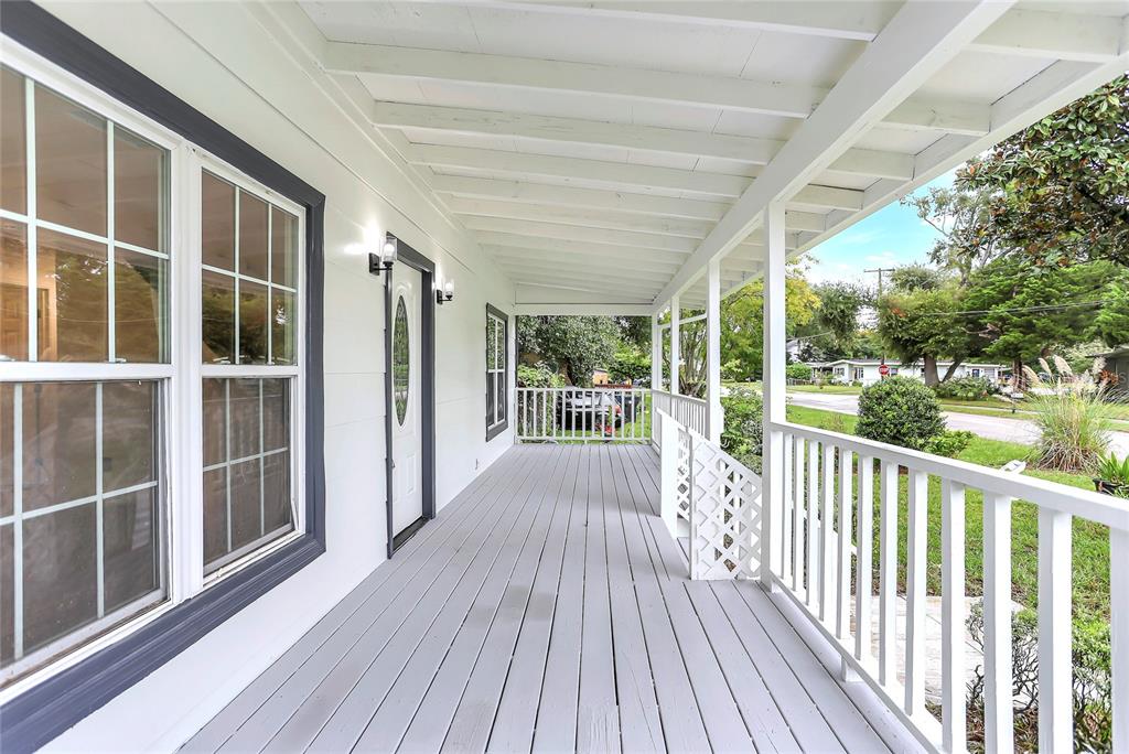A covered front porch with gray wooden decking, white railings, and a white front door — 1920 BAXTER AVENUE, ORLANDO, FL