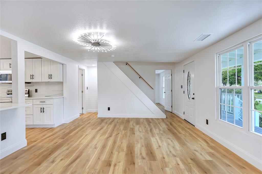 A bright, open-concept room features white cabinetry, light wood flooring, and a modern ceiling light — 1920 BAXTER AVENUE, ORLANDO, FL