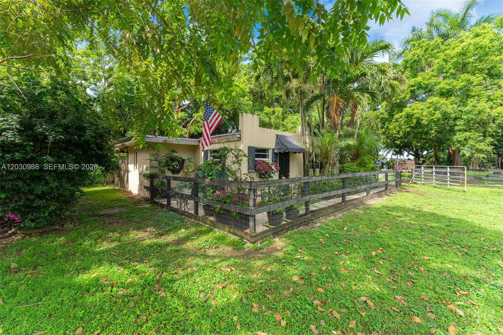 A small, light-colored house with a fenced yard and an American flag — 22065 SW 167th Ave # A, Miami FL 33170, MIAMI, FL