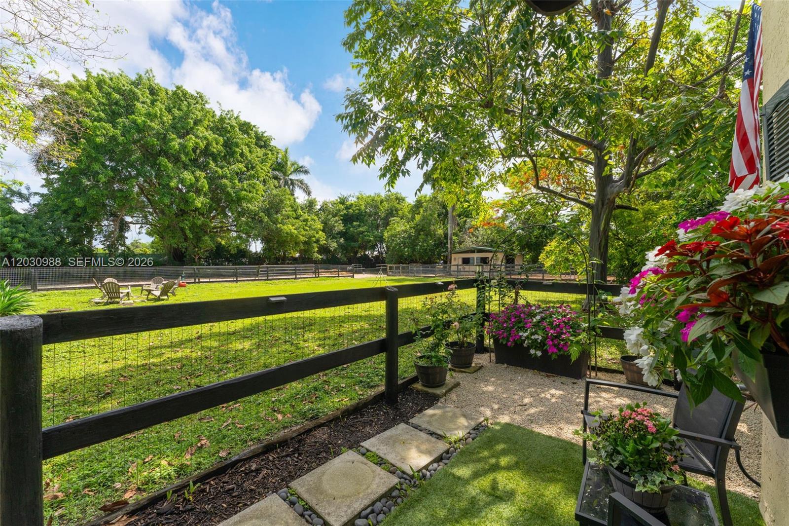 A fenced backyard features a gravel patio, potted flowers, and a grassy lawn with trees — 22065 SW 167th Ave # A, Miami FL 33170, MIAMI, FL