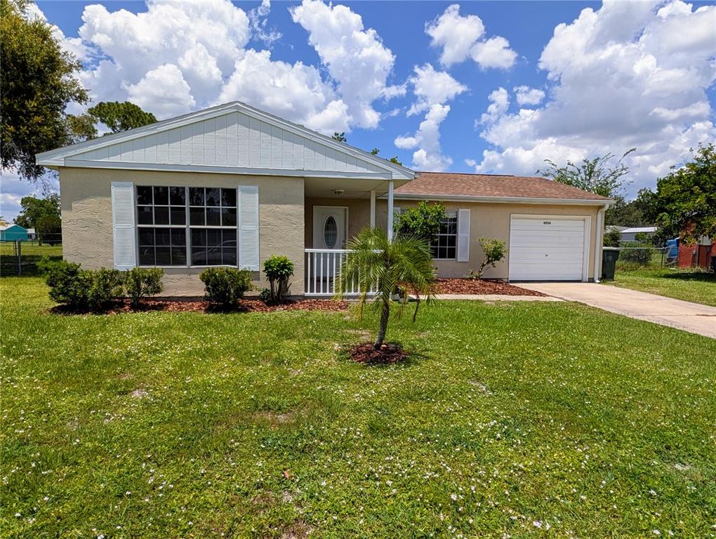 A single-story house with a tan exterior, white shutters, a front porch, and a garage — 6734 STARDUST AVENUE, NORTH PORT, FL