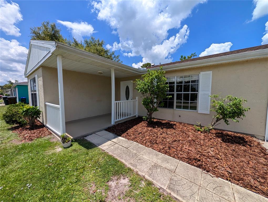 A tan house features a covered front porch, white railings, and a paved walkway — 6734 STARDUST AVENUE, NORTH PORT, FL