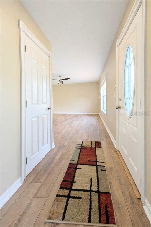 An entryway with wood-look flooring leads into a living area with a ceiling fan — 6734 STARDUST AVENUE, NORTH PORT, FL