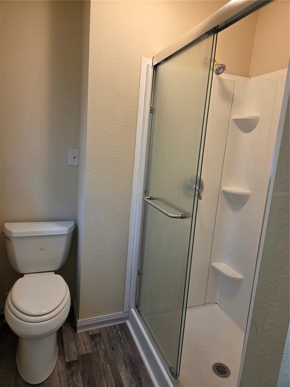 A bathroom features a white toilet next to a glass-enclosed shower with white walls — 5809 J G ROGERS LANE, PLANT CITY, FL