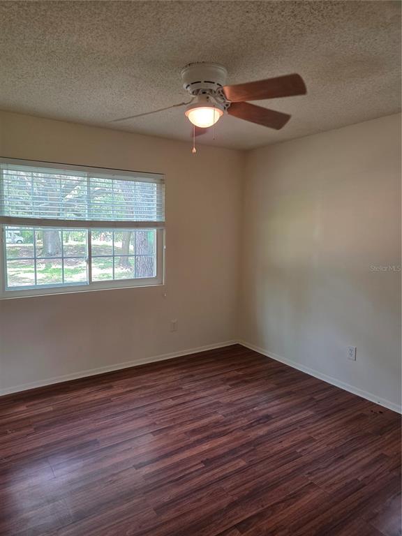 An empty bedroom features wood-look laminate flooring, a ceiling fan, and a window with blinds — 5809 J G ROGERS LANE, PLANT CITY, FL