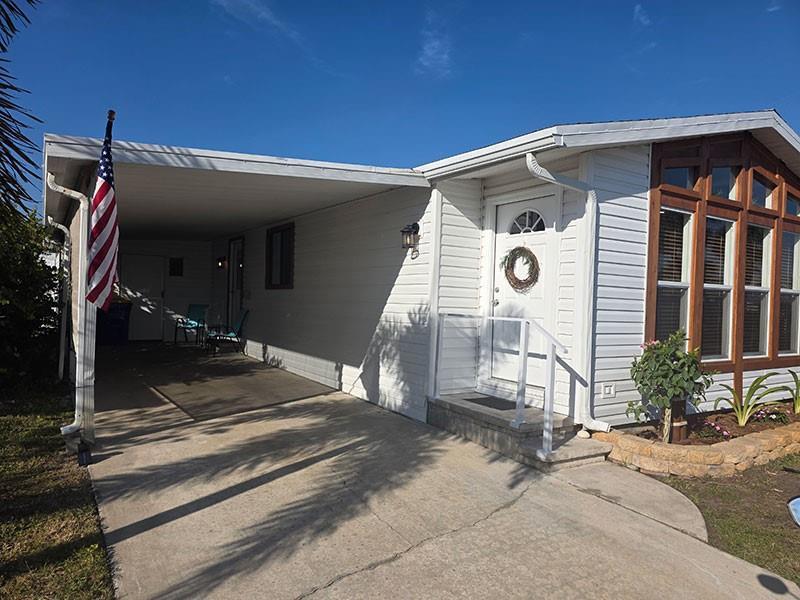 A white mobile home features a carport, a front door with a wreath, and large windows — 4300 SE Saint Lucie Boulevard # 70, Stuart FL 34997, STUART, FL