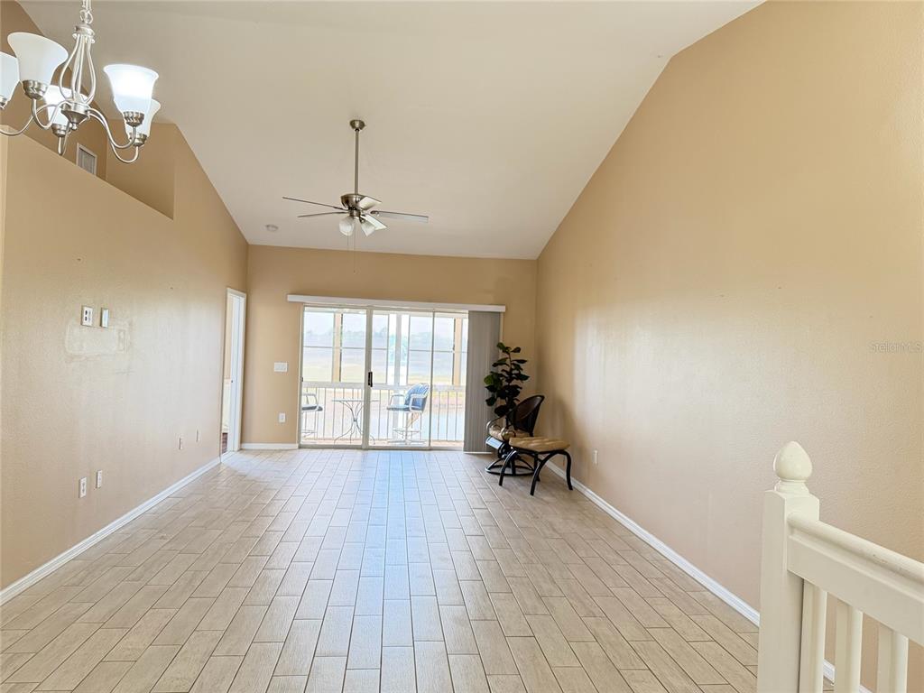 A living room with vaulted ceilings, tile flooring, a ceiling fan, and sliding glass doors — 315 EAGLE RIDGE ROAD, DAVENPORT, FL