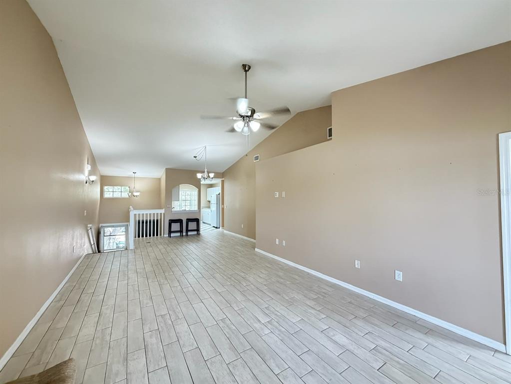 A spacious living area features vaulted ceilings, light-colored tile flooring, and a ceiling fan — 315 EAGLE RIDGE ROAD, DAVENPORT, FL