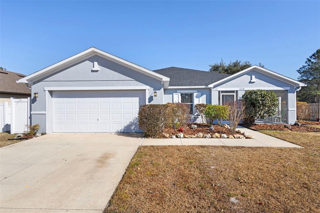 A single-story house with a light blue exterior, a two-car garage, and a front yard — 3339 CROTON AVENUE, DELTONA, FL