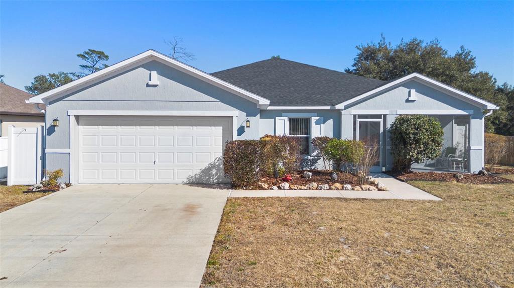 A single-story house with a two-car garage, light blue siding, and a screened-in front porch — 3339 CROTON AVENUE, DELTONA, FL