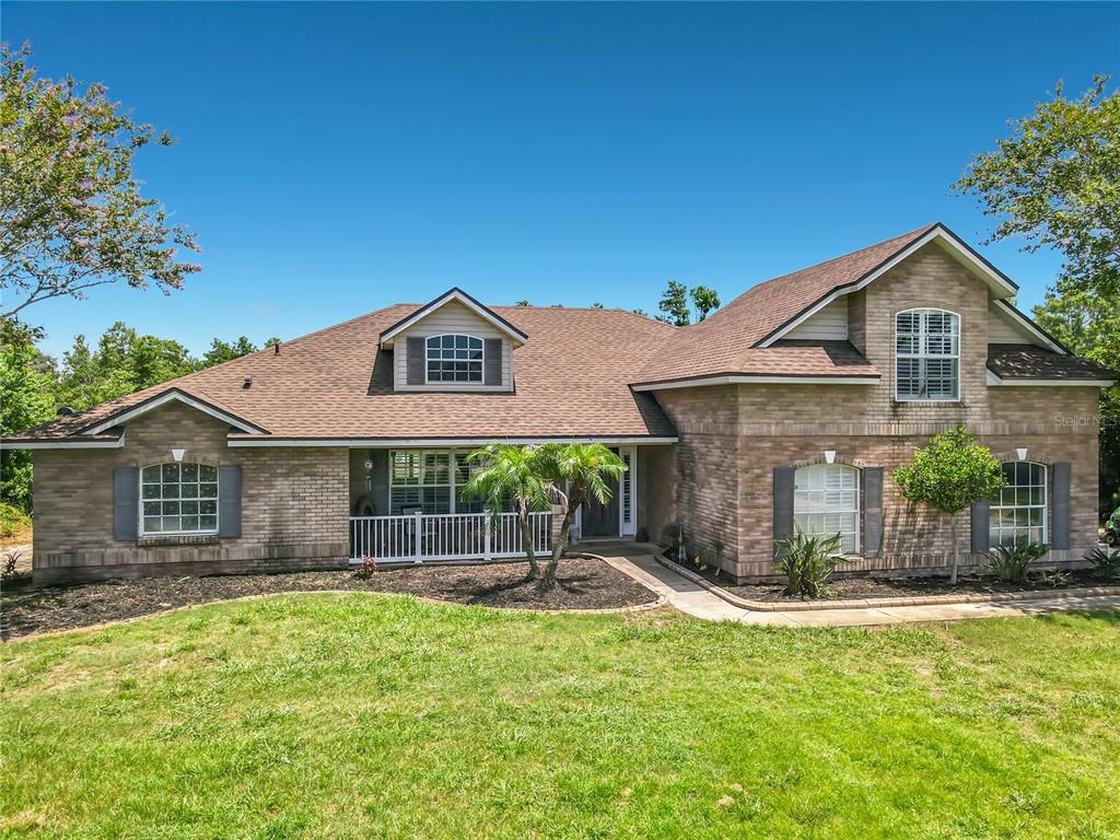 A two-story brick house with a brown shingled roof and a front lawn — 3000 LOCKWOOD BOULEVARD, DELTONA, FL