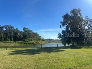 A grassy lawn leads to a black metal fence overlooking a pond and wooded area — 105 CEDAR HEIGHTS COURT, SANFORD, FL