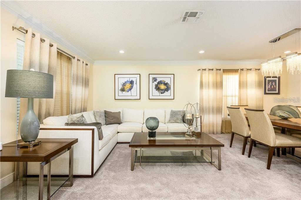 A living and dining area features a white sectional sofa, coffee table, and dining set — 105 CEDAR HEIGHTS COURT, SANFORD, FL