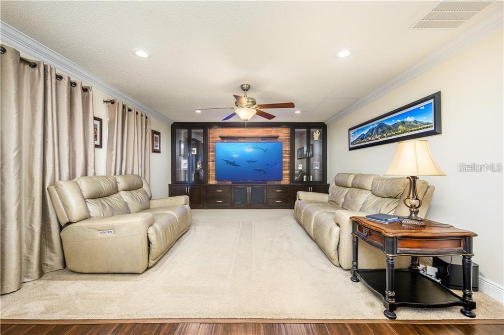 A living room features two beige leather sofas, a large built-in entertainment center, and carpeting — 105 CEDAR HEIGHTS COURT, SANFORD, FL