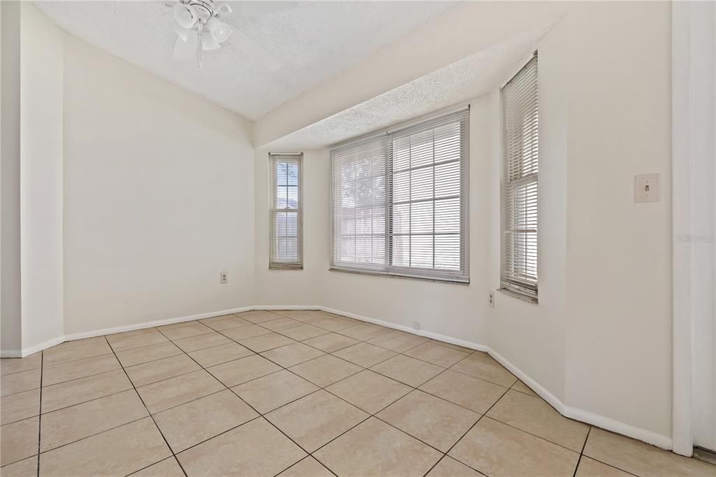 An empty room with beige tile flooring, white walls, and a bay window — 7607 GLADES COURT, TAMPA, FL