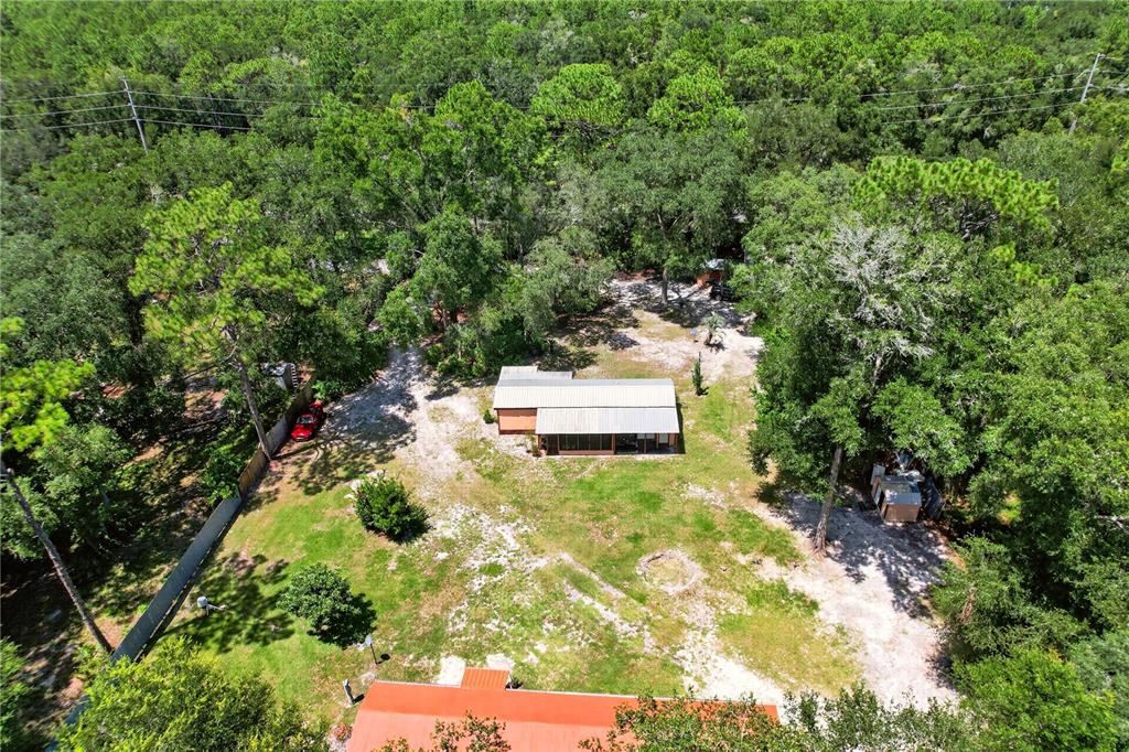 An aerial view shows a single-story house with a metal roof surrounded by wooded land — 8200 SE 145 STREET, DUNNELLON, FL