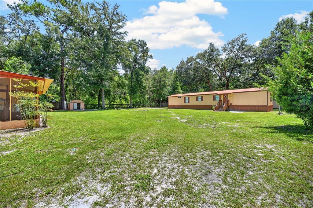 A large grassy yard features a mobile home, a small shed, and a screened porch — 8200 SE 145 STREET, DUNNELLON, FL