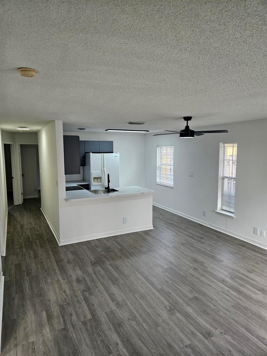 A kitchen with dark cabinets and a white peninsula overlooks a living area with gray flooring — 5665 Boynton Cove Way, Boynton Beach FL 33437, BOYNTON BEACH, FL